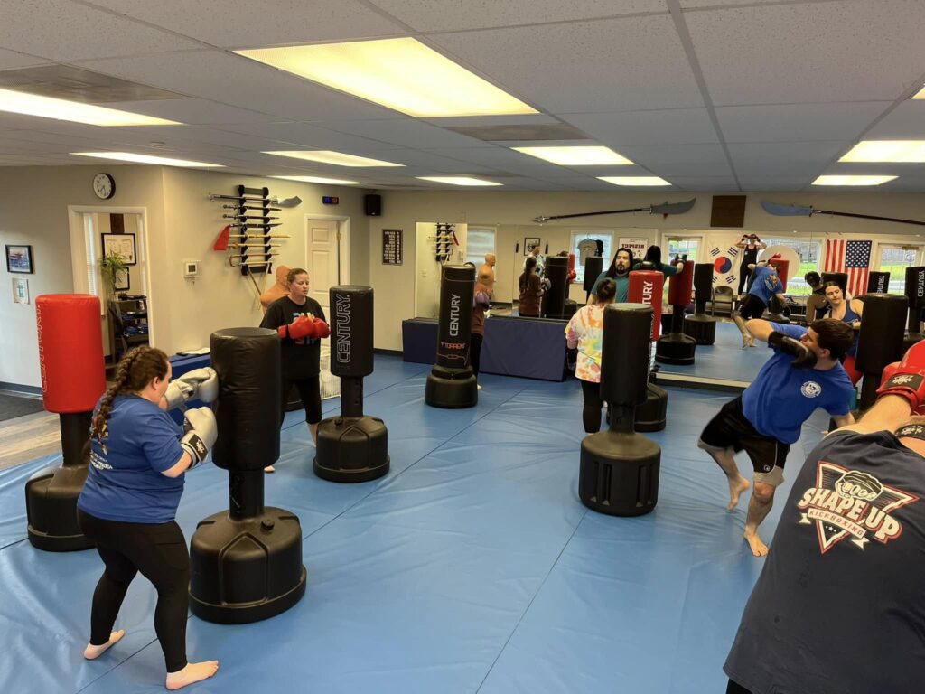 Motivated woman tracking workout progress with journal and kickboxing gloves nearby